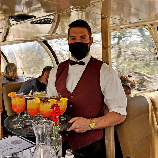 man serving cocktail drinks inside train cape cod island